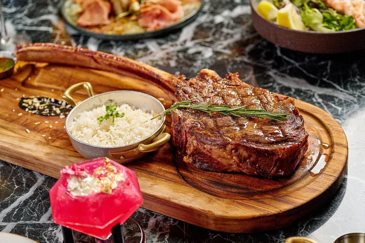 Grilled tomahawk steak with sides at Lo D'Alex Miami