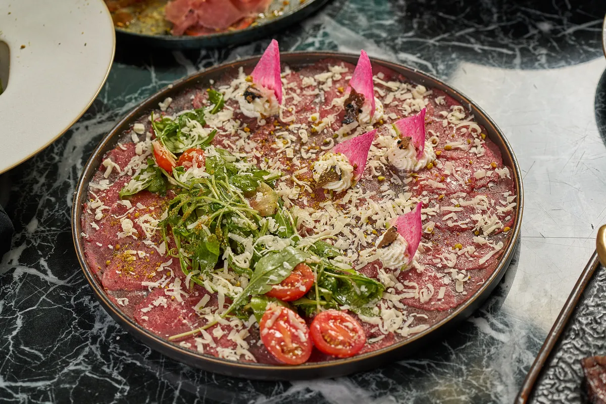 Wagyu Beef Carpaccio thinly sliced with truffle oil, parmesan and arugula — signature appetizer at Lo D'Alex Restaurant on Calle 8, Little Havana Miami